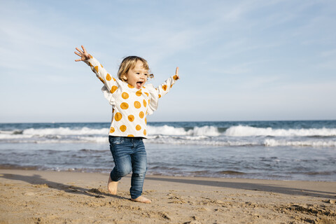 Glückliches kleines Mädchen läuft barfuß am Strand, lizenzfreies Stockfoto