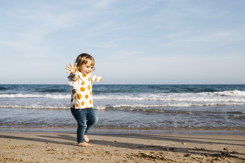 Glückliches kleines Mädchen läuft barfuß am Strand, lizenzfreies Stockfoto