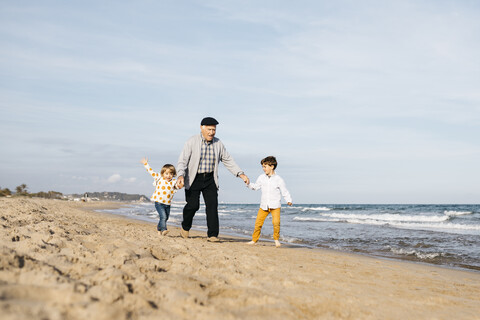 Grandfather having fun with his grandchildren on the beach stock photo