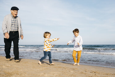 Grandfather strolling on the beach with his grandchildren - JRFF03206