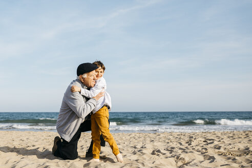 Grandfather and grandson hugging on the beach - JRFF03216