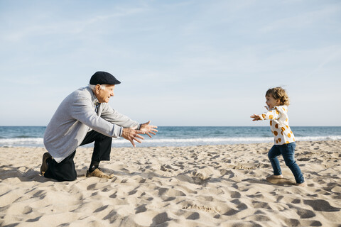 Großvater spielt mit seiner Enkelin am Strand, lizenzfreies Stockfoto