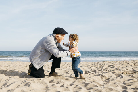 Großvater spielt mit seiner Enkelin am Strand, lizenzfreies Stockfoto