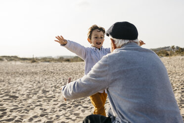 Portrait of little boy running into his grandfather's arms on the beach - JRFF03219