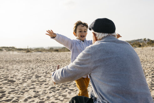 Porträt eines kleinen Jungen, der seinem Großvater am Strand in die Arme läuft - JRFF03219