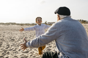 Porträt eines glücklichen kleinen Jungen, der seinem Großvater am Strand in die Arme läuft - JRFF03221