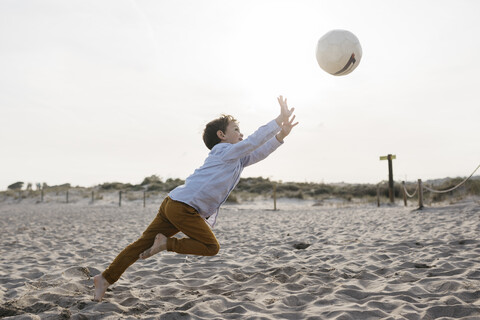 Little boy playing soccer on the beach stock photo