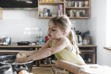 Little girl rolling out dough in the kitchen - KMKF00907