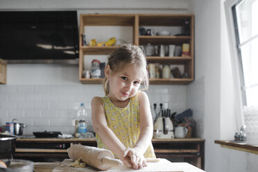 Portrait of smiling little girl kneading dough in the kitchen - KMKF00908