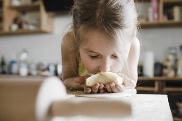 Little girl smelling freshly prepared stuffed pastry - KMKF00910