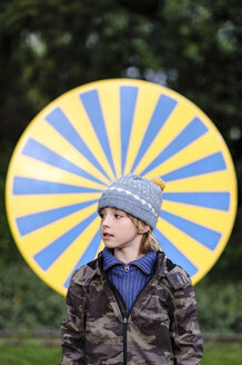 Porträt eines Jungen in warmer Kleidung vor einem gelben und blauen Kreis - EYAF00194