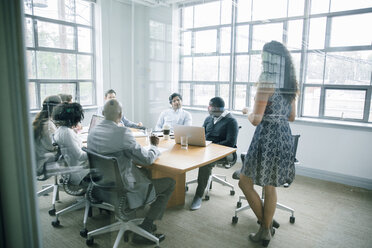 Businesswoman talking behind window in meeting - BLEF02089