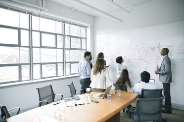 Business people talking near whiteboard in meeting - BLEF02094