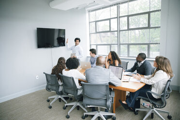 Businessman talking near visual screen in meeting - BLEF02097