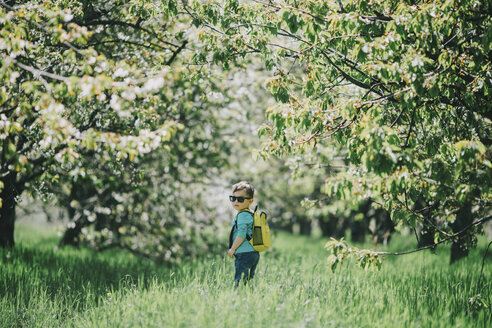 Kaukasischer Junge mit Sonnenbrille und Rucksack im Gras - BLEF02104