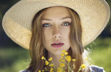 Caucasian woman wearing hat holding wildflowers - BLEF02141