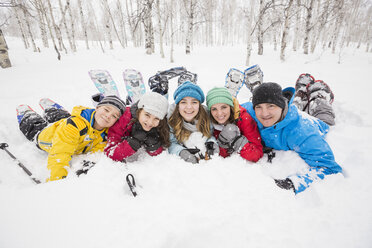 Porträt einer lächelnden kaukasischen Familie, die im Schnee liegt - BLEF02142