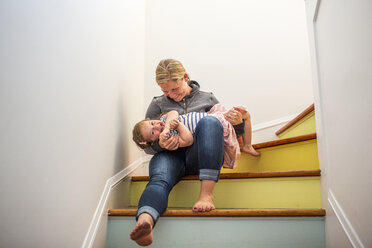 Kaukasische Mutter und Tochter spielen auf einer mehrfarbigen Treppe - BLEF02175