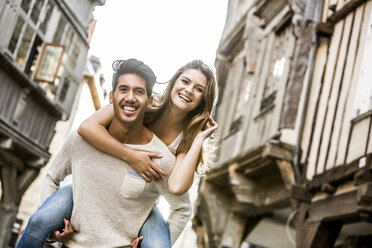 Man carrying woman piggyback in city - BLEF02225