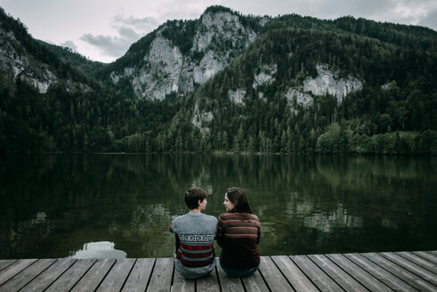 Caucasian couple sitting on dock near scenic view of mountain - BLEF02271