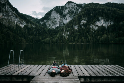 Caucasian couple laying on dock near scenic view of mountain - BLEF02272