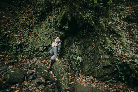 Kaukasische Frau sitzt im Wald und hält einen Ast, lizenzfreies Stockfoto