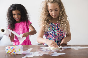 Girls cleaning spilled milk on table - BLEF02312