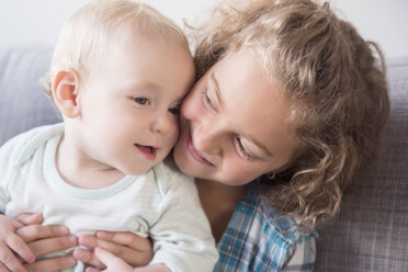 Smiling Caucasian girl holding baby brother - BLEF02319