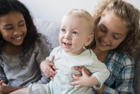 Friend watching smiling girl holding baby brother - BLEF02320