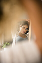 Reflection in mirror of Mixed Race woman holding hair - BLEF02347