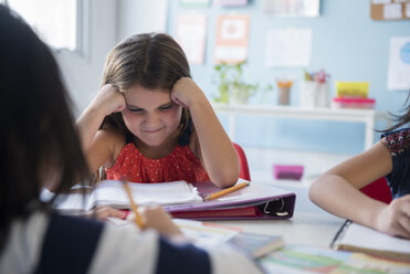 Frustriertes Mädchen starrt in der Schule auf ein Notizbuch - BLEF02357
