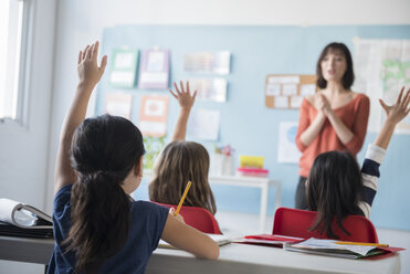 Girls raising hand for teacher in classroom - BLEF02361