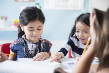 Girls reading notebook in classroom - BLEF02362