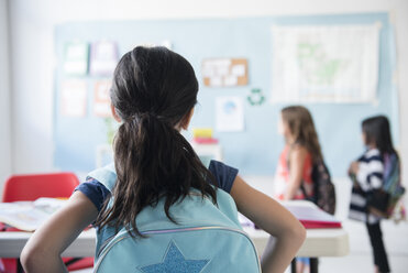 Mädchen im Klassenzimmer mit Rucksack beobachtet Mitschüler - BLEF02364