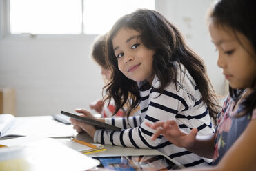 Porträt eines lächelnden Mädchens, das ein digitales Tablet im Klassenzimmer benutzt - BLEF02376