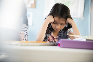 Frustrated girl with head in hands in classroom - BLEF02377