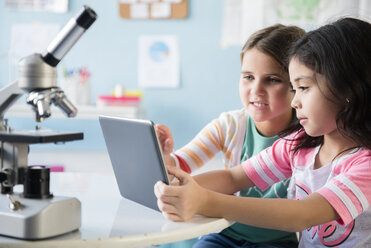 Kaukasische Mädchen teilen sich ein digitales Tablet im Klassenzimmer - BLEF02384