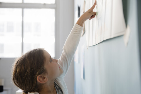 Caucasian girl pointing to paper on wall stock photo