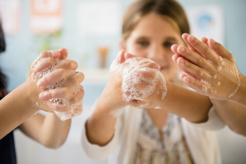 Girls washing hands with soap stock photo