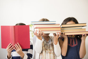 Girls holding books in front of faces - BLEF02392