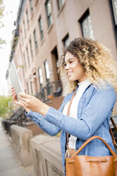 Gemischtrassige Frau in der Stadt posiert für ein Selfie mit digitalem Tablet - BLEF02398