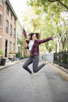 Gemischtrassige Frau springt vor Freude in der Stadt - BLEF02402