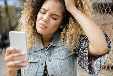 Unhappy Mixed Race woman texting on cell phone - BLEF02414