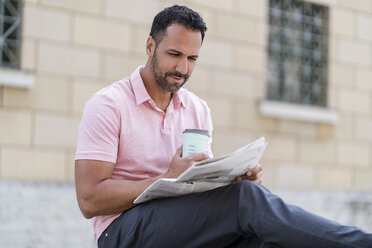 Mann mit Kaffee zum Mitnehmen liest Zeitung in der Stadt - DIGF06948