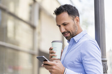 Businessman with with takeaway coffee and cell phone in the city - DIGF06955