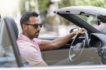 Portrait of man wearing sunglasses driving convertible - DIGF06984