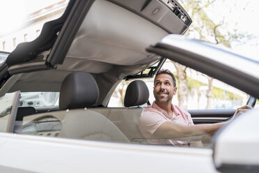 Man sitting in car with closing convertible top - DIGF06990