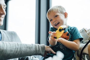 Arm der Mutter kitzelt Sohn mit Spielzeugauto - BLEF02494