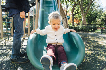 Mixed Race father watching son on playground slide - BLEF02500