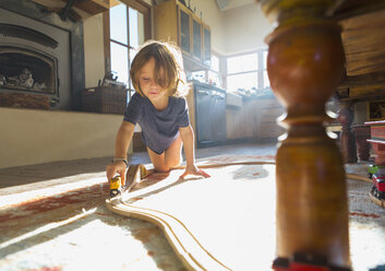 Kaukasischer Junge spielt mit Spielzeug-Rennbahn auf dem Boden - BLEF02529
